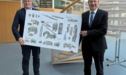Landrat Heiner Scheffold und der Leiter des Amtes für Kreisentwicklung, Wolfgang Koller, halten eine übergroße Version der neuen Sonderbriefmarke